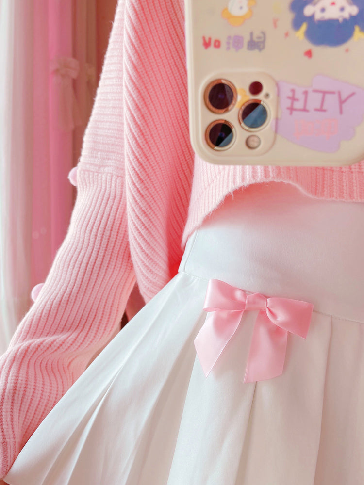 Close-up of the model holding up the pleats of the Sweetheart Academy Skort to show fabric and bow detail