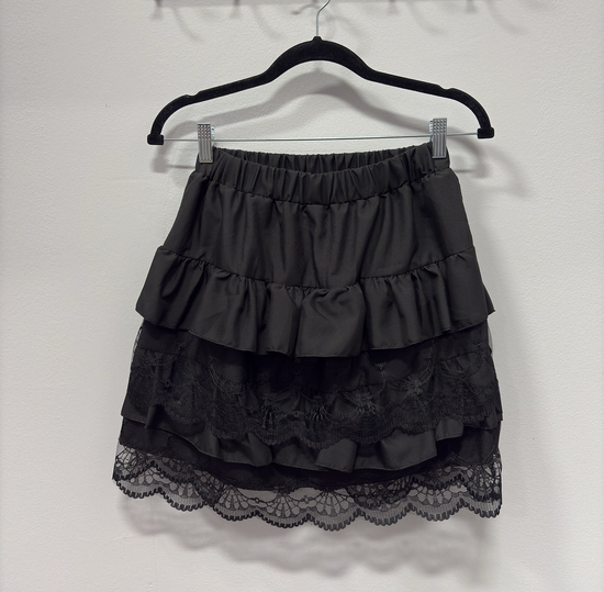 The Frosted Layers Ruffle Skort in black on a hanger.