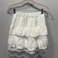 The Frosted Layers Ruffle Skort in white on a hanger.