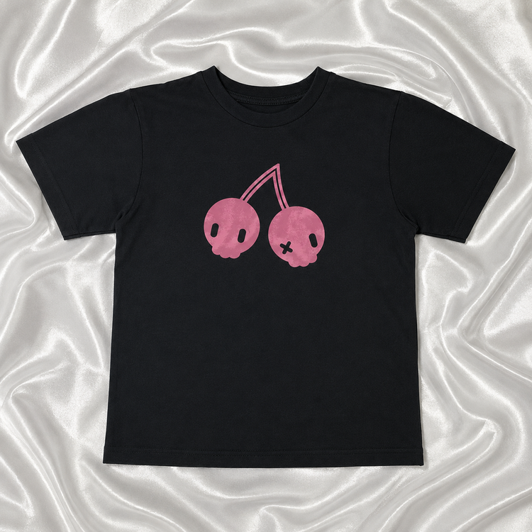 Flat lay of the Sweet Decay Cherry Tee on top of white satin fabric.