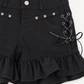 Close-up of Two Moody Originals: Pretty Dangerous Shorts showing skull embellishments, studded ribbon lacing, and ruffle trim details.