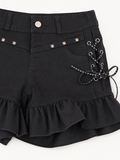 Close-up of Two Moody Originals: Pretty Dangerous Shorts showing skull embellishments, studded ribbon lacing, and ruffle trim details.