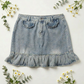 Front flat lay of the Two Moody Originals: Ruffle Flare Jean Skirt surrounded by small bunches of flowers.