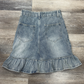 Back flat lay of the Two Moody Originals: Ruffle Flare Jean Skirt with Angled Front in size S with ruffle hem.