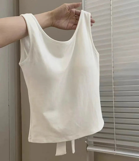 White Backstage Bow Backless Tank hanging from a model's arm, displaying the front.