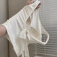 Hanging side view of the white Backstage Bow Backless Tank, highlighting the built-in bra and open back.