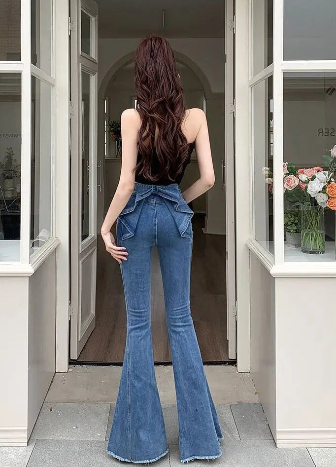 Model in a doorway showcasing the back view of the Dark Blue Backstage Bow Flare Jeans.
