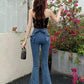 Model standing in front of flowers, showing the back view of the Dark Blue Backstage Bow Flare Jeans, showcasing the bow detail.