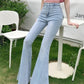 Model leaning on a table in the light Blue Backstage Bow Flare Jeans.