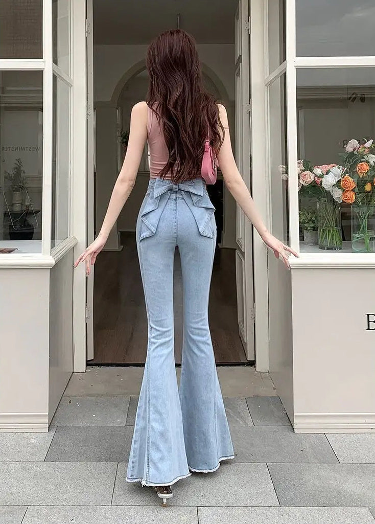 Model in a doorway showing the back view of the Light Blue Backstage Bow Flare Jeans highlighting the bow accent.