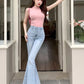 Model posing in a doorway wearing the Light Blue Backstage Bow Flare Jeans, front view.