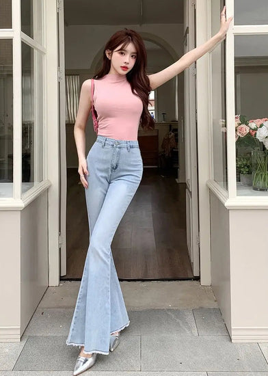 Model posing in a doorway wearing the Light Blue Backstage Bow Flare Jeans, front view.