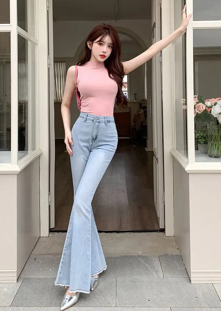 Model posing in a doorway wearing the Light Blue Backstage Bow Flare Jeans, front view.