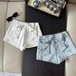 White and light blue Backstage Bow Shorts laid flat.