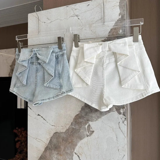 Light blue and white color options of the Backstage Bow Shorts hanging together.