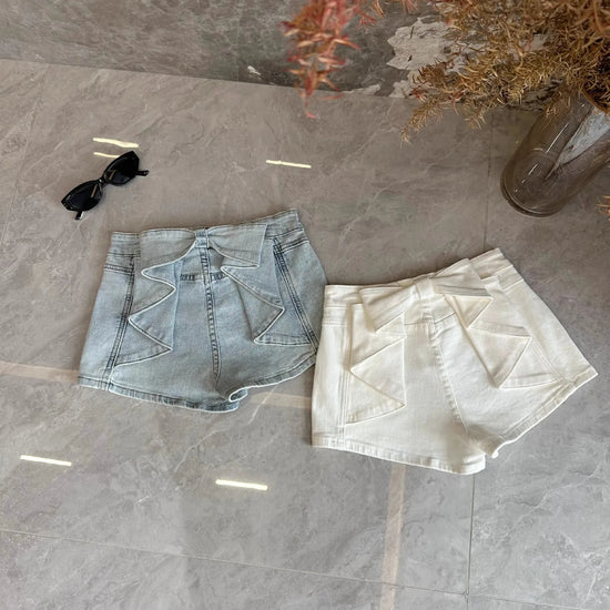 Overhead flat lay of the Backstage Bow Shorts in white and light blue.