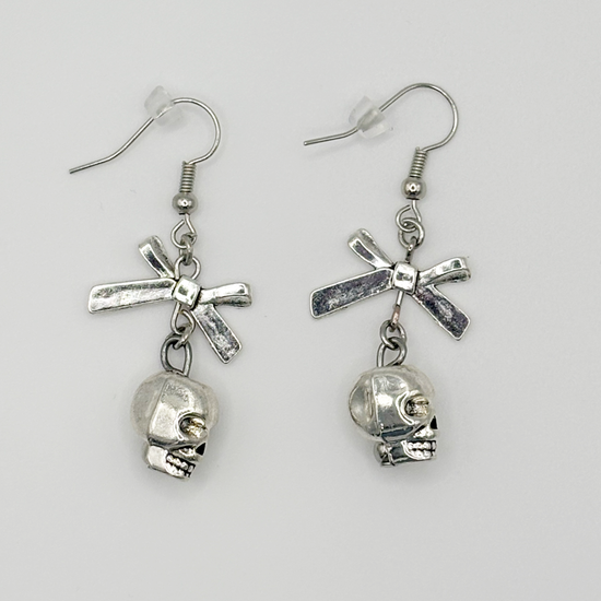 Side profile of the Bad to the Bow Earrings, featuring silver-plated skull charms with bow accent
