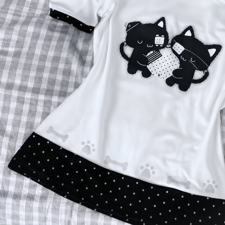Close-up view of the Bandaged Kitties Off-Shoulder Top, highlighting the bandaged kitty graphic, contrasting polka dot trim, and decorative paw print and bone accents along the hem.