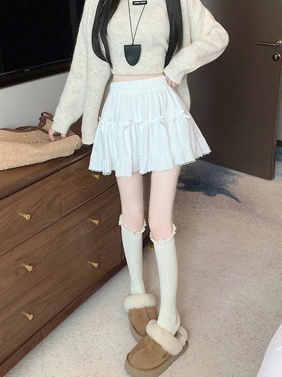 Front view of a model standing in a bedroom in the Bow Peep Mini Skort in White.
