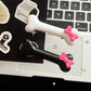 Black and white Bowtiful Bones Hair Clips displayed together, featuring glossy bone-shaped designs with pink bow accents.
