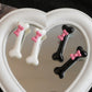 Mixed black and white Bowtiful Bones Hair Clips, displayed together on a heart-shaped mirror, showcasing glossy bone-shaped designs and pink bow accents.