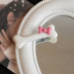 Close-up of the white Bowtiful Bones Hair Clip, featuring a glossy bone-shaped design with a pink bow accent.