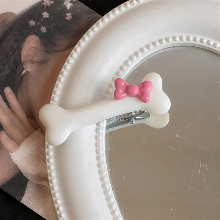 Close-up of the white Bowtiful Bones Hair Clip, featuring a glossy bone-shaped design with a pink bow accent.