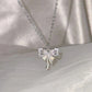 The Celestial Ribbon Bow Necklace, a silver crystal bow pendant necklace, displayed above soft white satin.