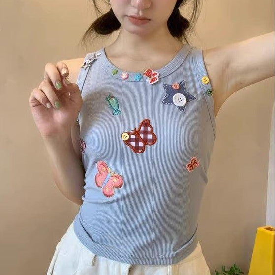 Front view of a model wearing the pale periwinkle blue Charm Collector Tank with white bottoms.