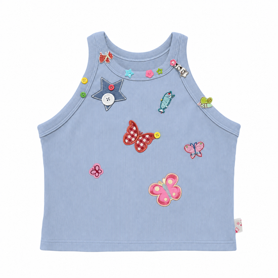 Pale periwinkle blue Charm Collector Tank shown in a front flat lay with colorful butterfly, star, animal, and button embellishments.