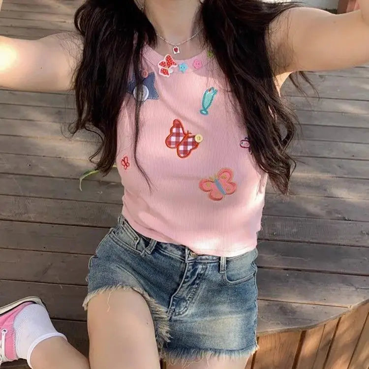 Model wearing the dusty pink Charm Collector Tank with denim shorts in a relaxed deck pose.