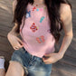 Seated model wearing the dusty pink Charm Collector Tank with denim shorts on a wooden deck.