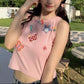 Front outdoor view of a model wearing the dusty pink Charm Collector Tank with denim bottoms.