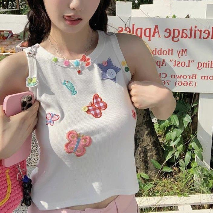 Close-up outdoor view of the white Charm Collector Tank showing its colorful patches and buttons.