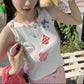 Model wearing the white Charm Collector Tank outdoors while holding a pink phone and bag.