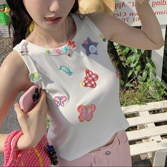 Model wearing the white Charm Collector Tank outdoors while holding a pink phone and bag.