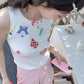 Overhead view of a model wearing the white Charm Collector Tank with pink shorts and accessories.