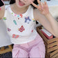 Seated model wearing the white Charm Collector Tank with pink pants in a close-up view.