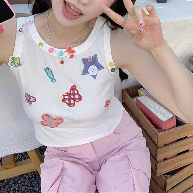 Seated model wearing the white Charm Collector Tank with pink pants in a close-up view.