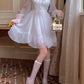 Model posing in the Cloudlight Fairy Dress while holding the dress and a small purse with an embellished bow and added sparkles