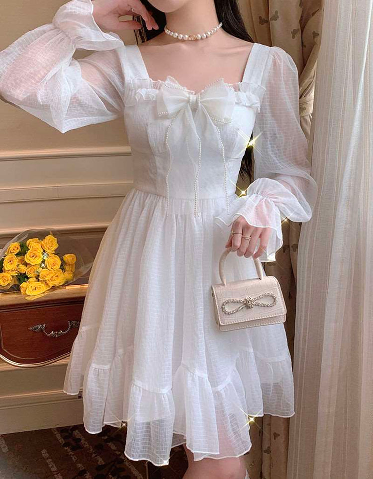 Model wearing the Cloudlight Fairy Dress while holding a mini purse with an embellished bow detail