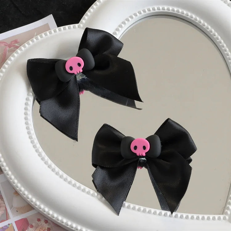 Creep It Cute Hair Bows — Pair of black satin skull hair bows arranged inside a heart-shaped mirror.