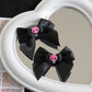 Creep It Cute Hair Bows — Pair of black satin skull hair bows reflected in a white heart mirror.