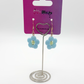 The Daisy Sky Earrings displayed on a card, highlighting the pastel blue flower design and delicate details.