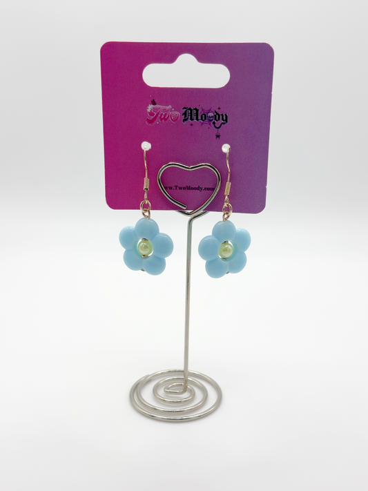 The Daisy Sky Earrings displayed on a card, highlighting the pastel blue flower design and delicate details.