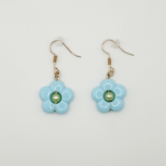 The Daisy Sky Earrings featuring soft blue daisy charms with a glossy finish in a lightweight, dreamy design.