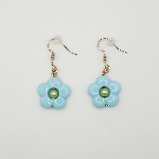 The Daisy Sky Earrings featuring soft blue daisy charms with a glossy finish in a lightweight, dreamy design.