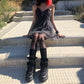 Model seated outdoors in Dark Fairy Tulle Dress, styled with black shoes, leg warmers, and a fishnet skull tights