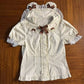 The Darling Honey Bear Blouse in apricot laid flat showing lace trim, bear-shape ears on the collar, and brown dotted bows.