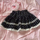 Dotted Doll Lace Skort arranged in a flat lay, showing the black polka-dot fabric, tiered shape, and contrasting white lace.